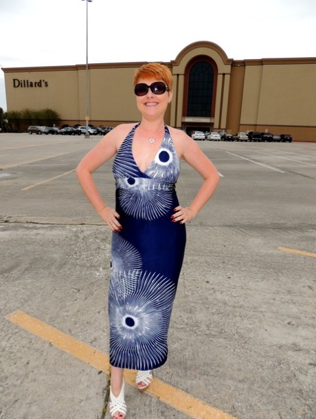 Caucasian woman with short red hair gives a blowjob in a dressing room