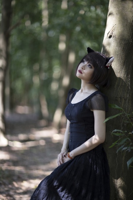 Pretty Asian model posing in her elegant black dress in the forest